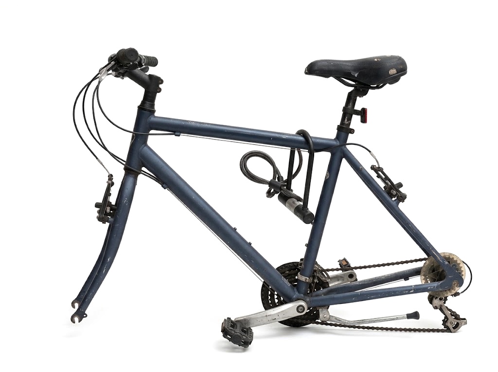 A bicycle frame still locked with a D-lock, both of its wheels stolen.